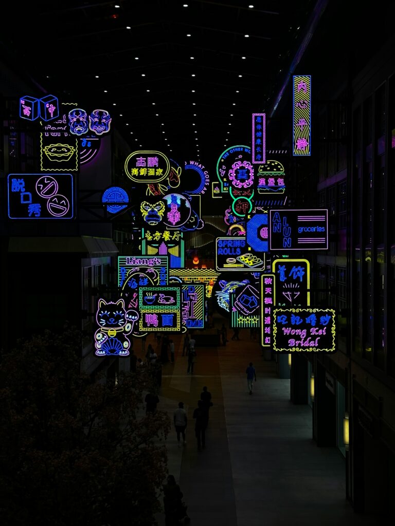 Neon lights and signs in dark walkway.